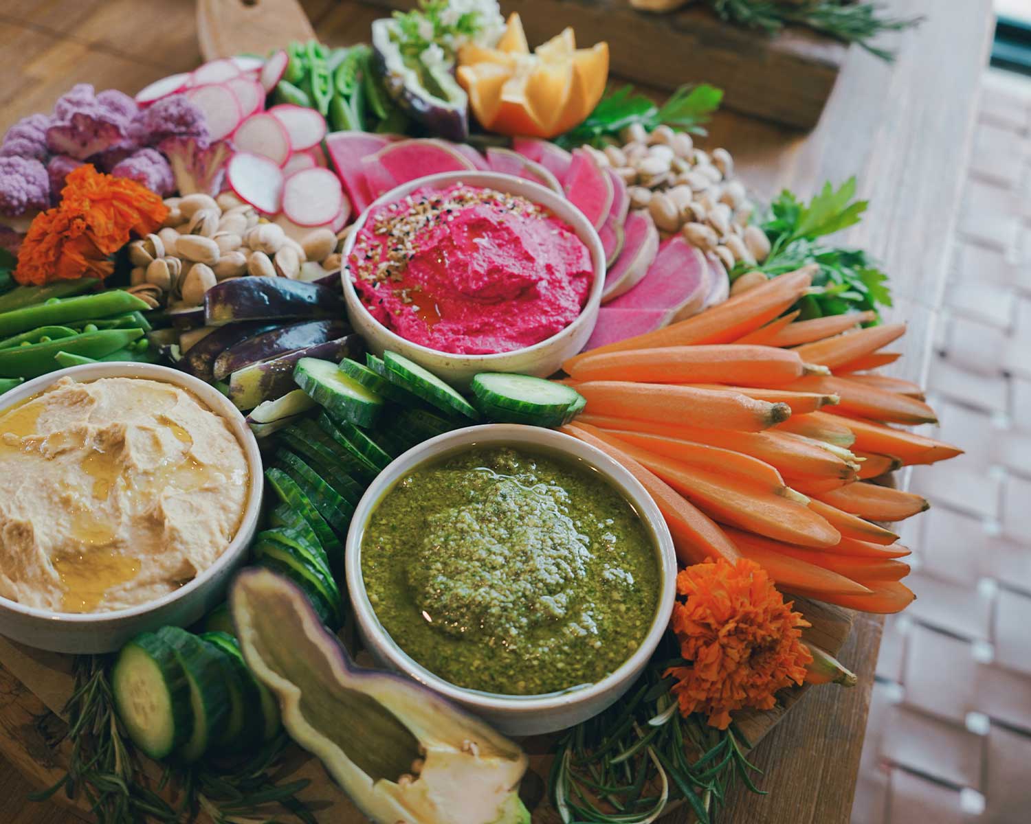 Platter of fresh vegetables and dips on a wooden board