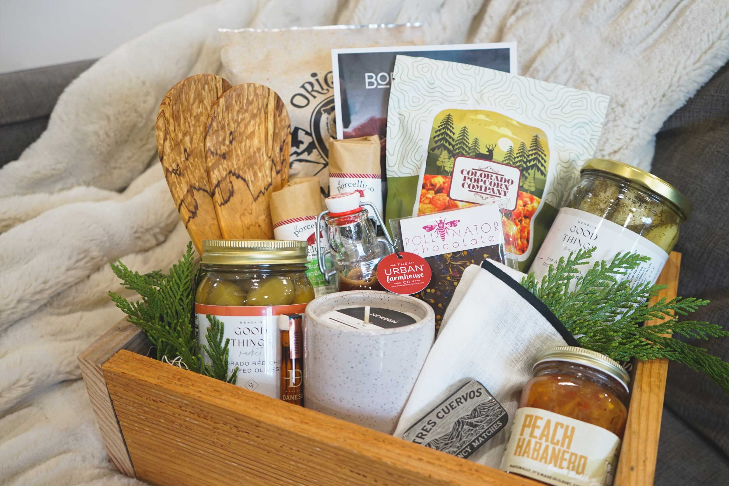 Gift basket with food items and a mug on a blanket