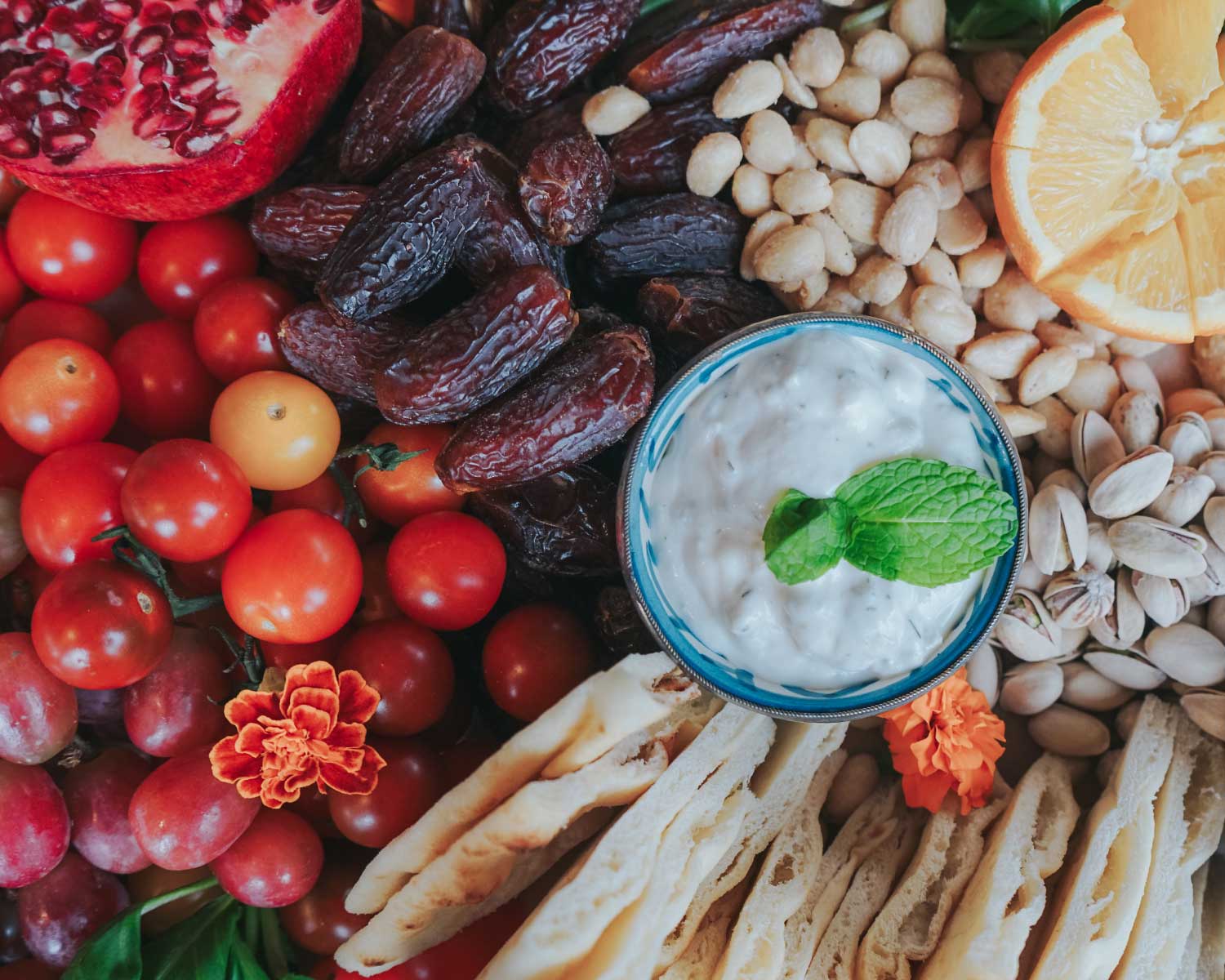 Assorted fruits, nuts, and a bowl of dip on a colorful background