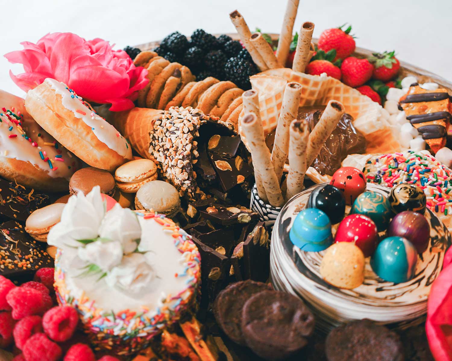 Assorted pastries and treats including donuts, cookies, and berries on a white background