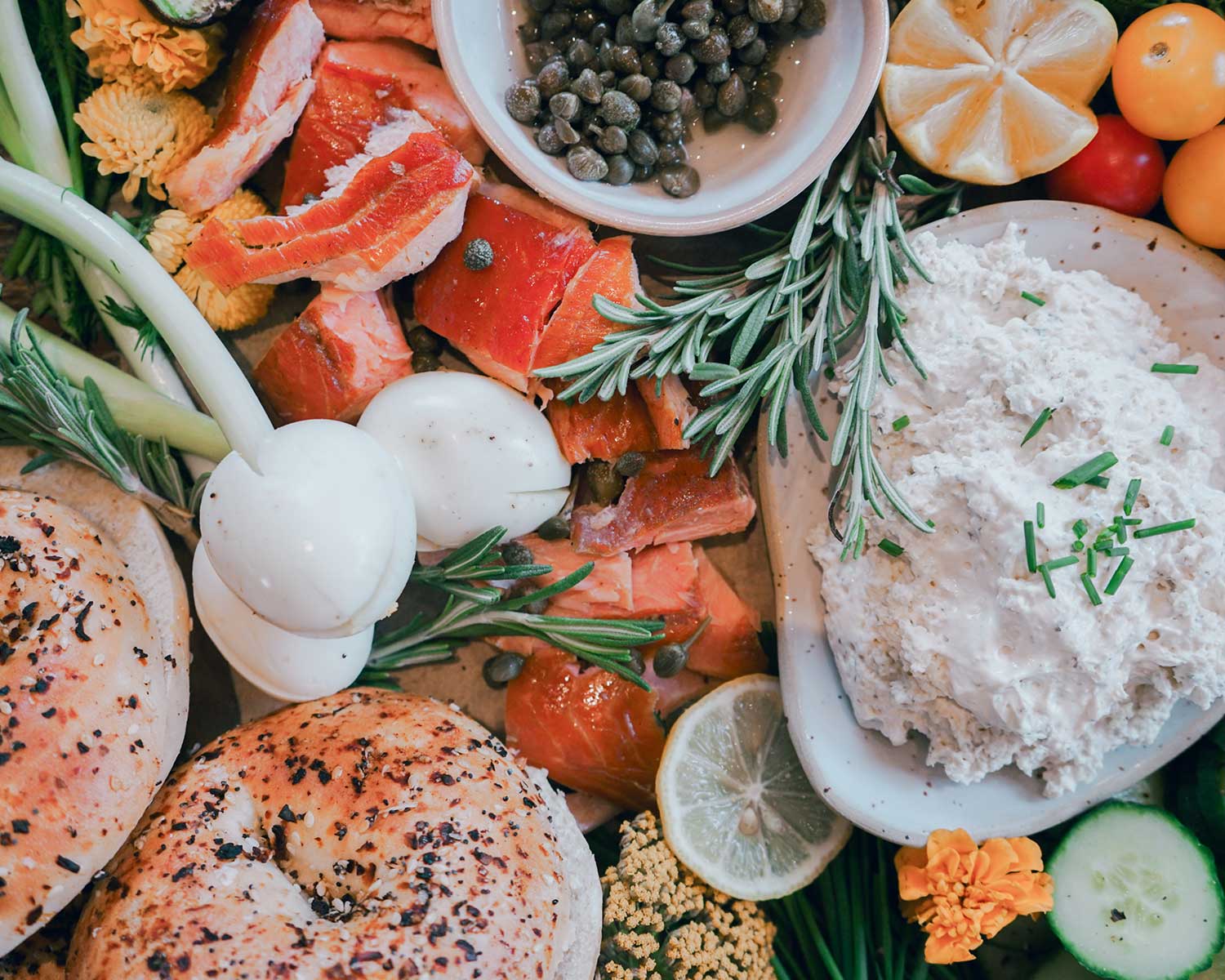 Assorted seafood and vegetables on a wooden board with herbs and lemon slices.