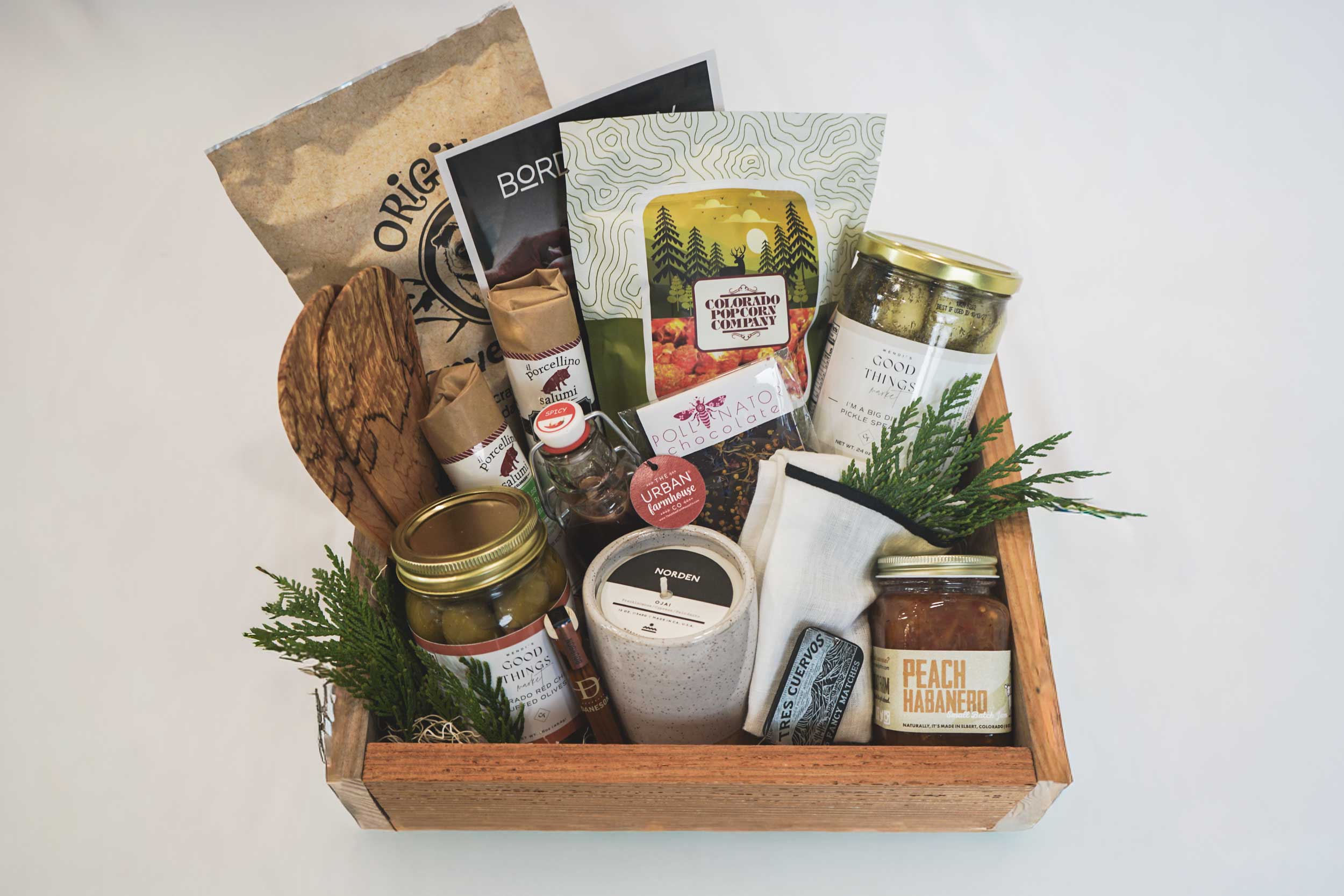 Gift basket with candles, snacks, and other items on a white background