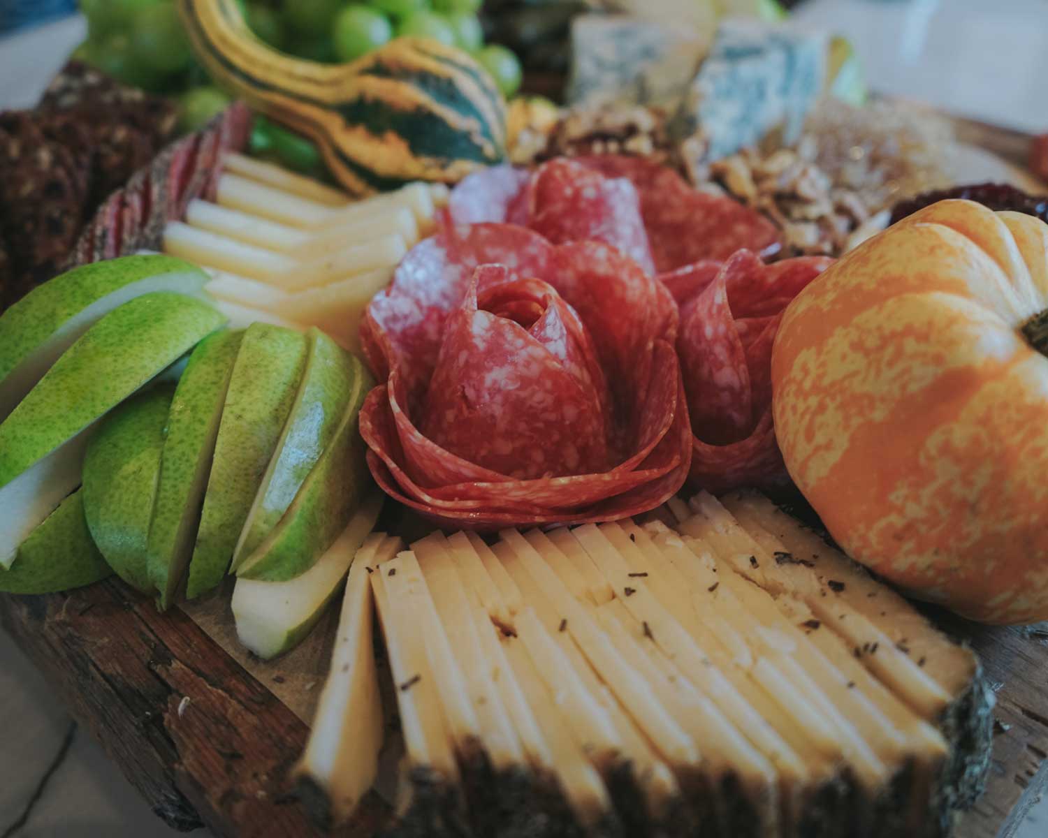 Platter with sliced apples, salami, and crackers on a wooden board.