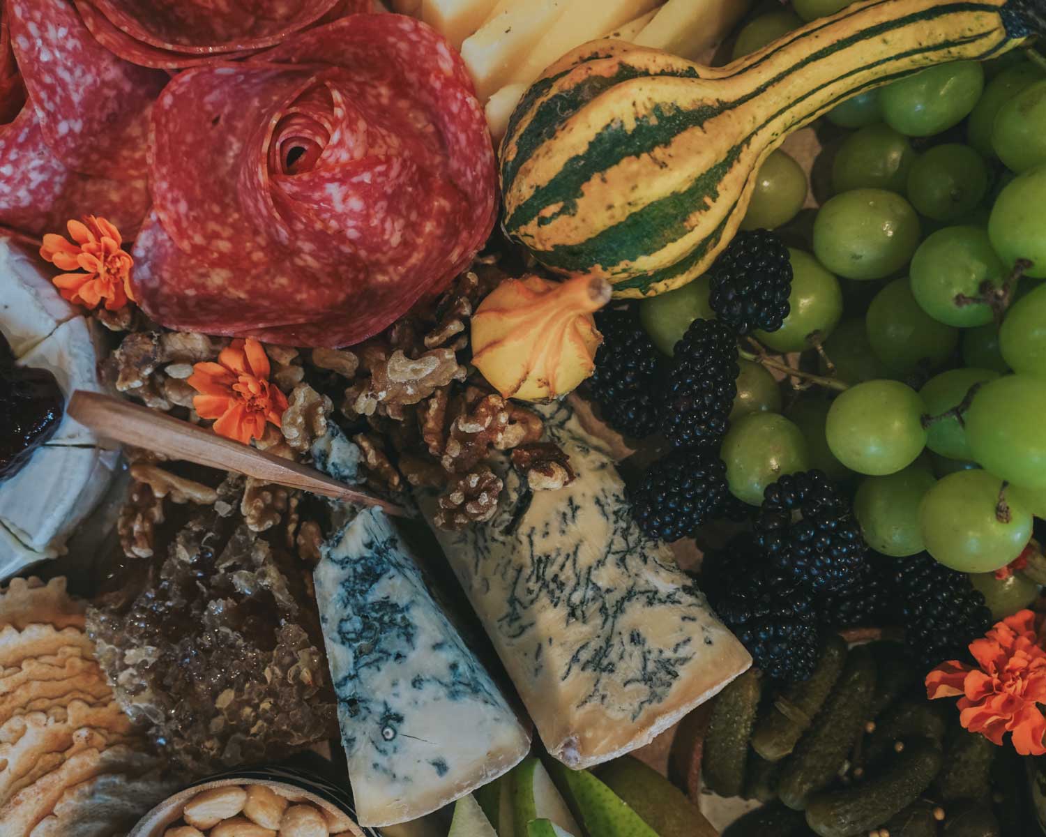Assorted meats, cheeses, and fruits on a platter with decorative elements.