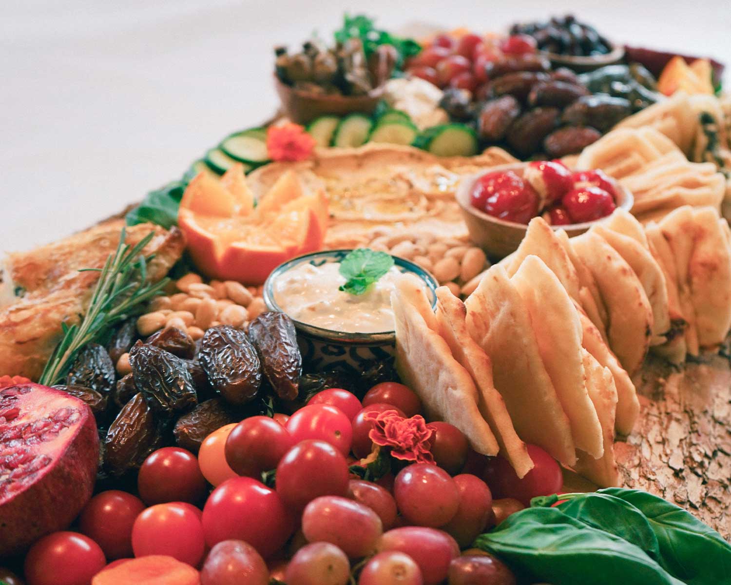 Assorted platter with bread, fruits, and dips on a white surface