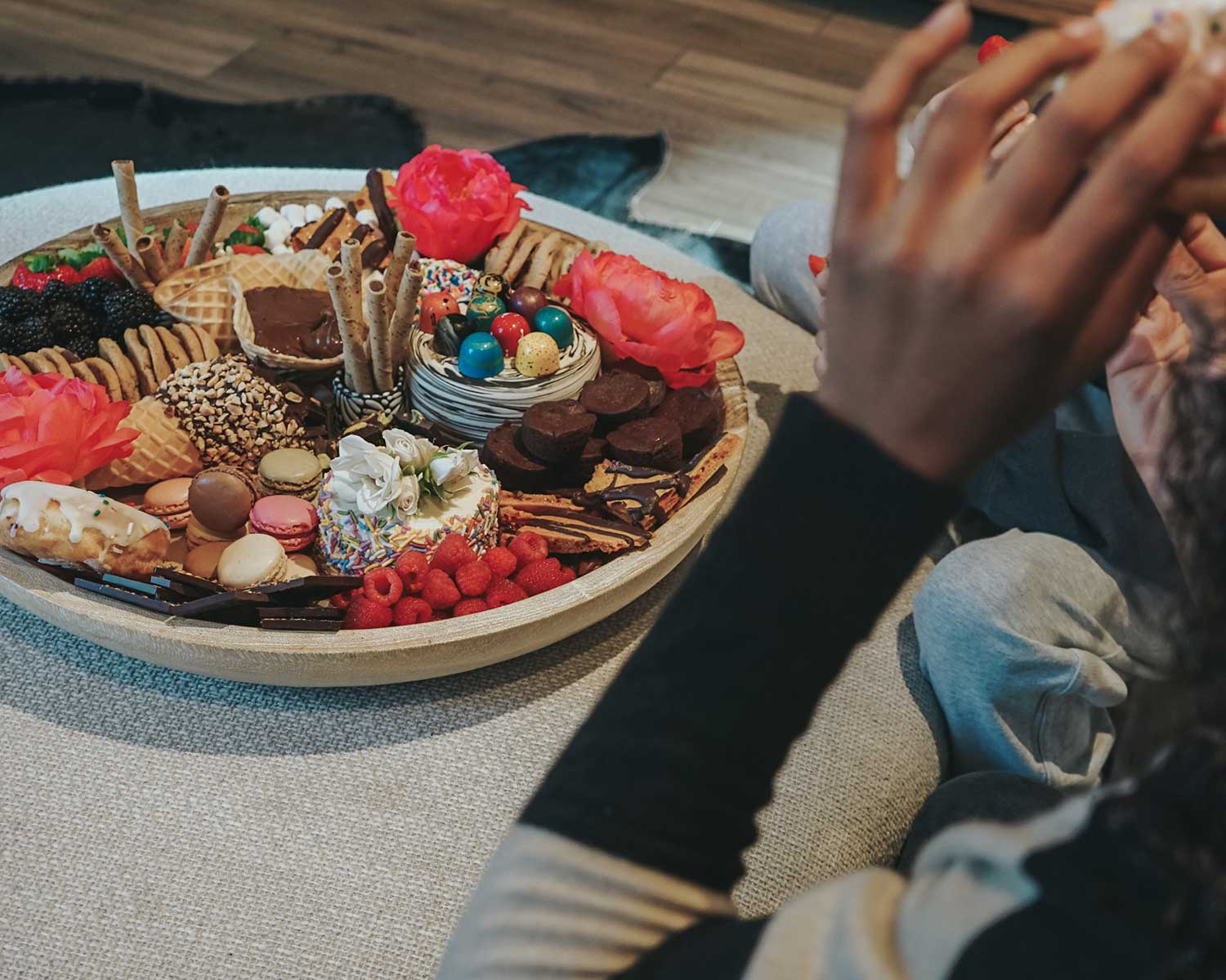 Person reaching for a dessert on a platter of various treats