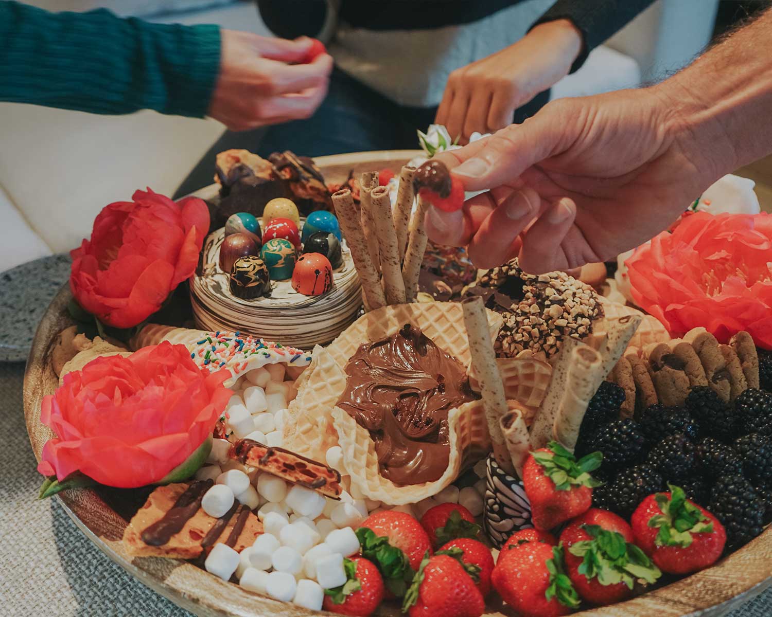 Dessert platter with various treats including strawberries, flowers, and waffles.